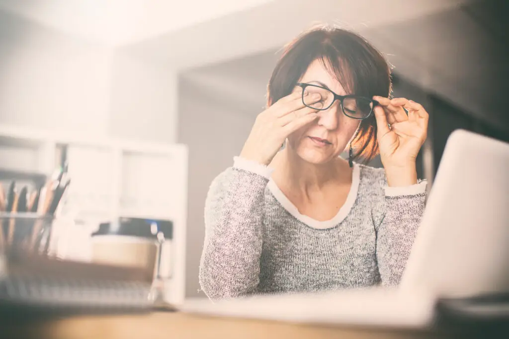tired woman rubbing eyes under glasses