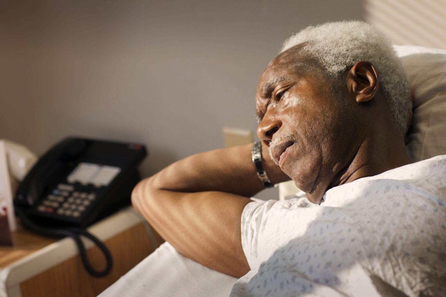 High angle view of thoughtful man lying on bed in hospital