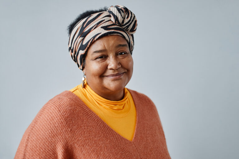 Portrait of black senior woman wearing ethnic prints and looking at camera smiling