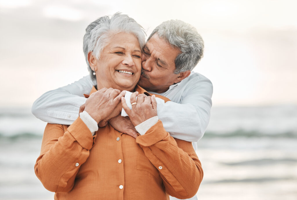 elderly Back couple embracing, smiling, on a beach