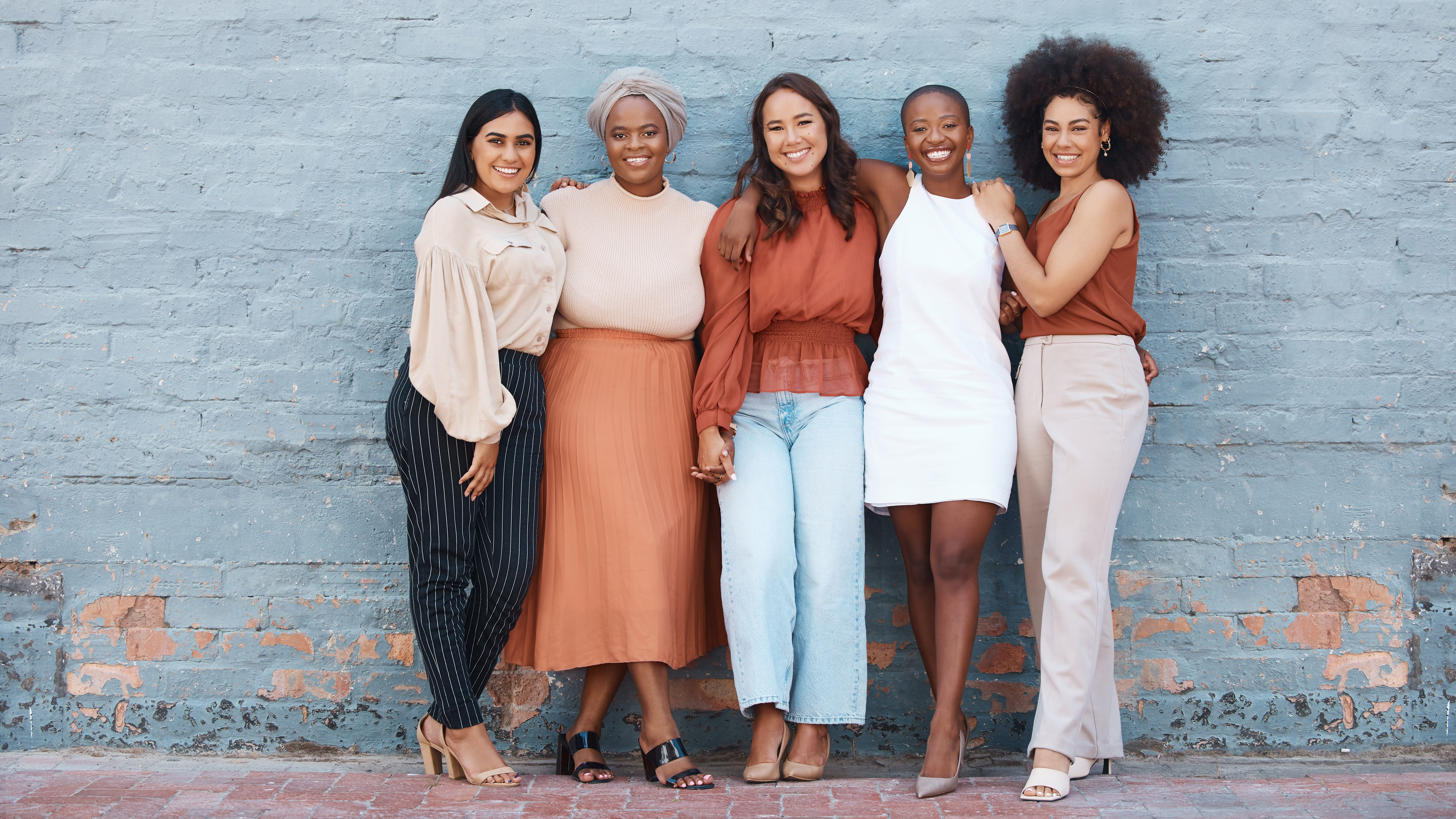 Group of 5 young adult women of diverse ethnicities embracing and smiling