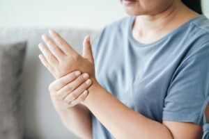 Closeup of woman sitting on sofa holds her wrist. hand injury, feeling pain. Health care and medical concept.