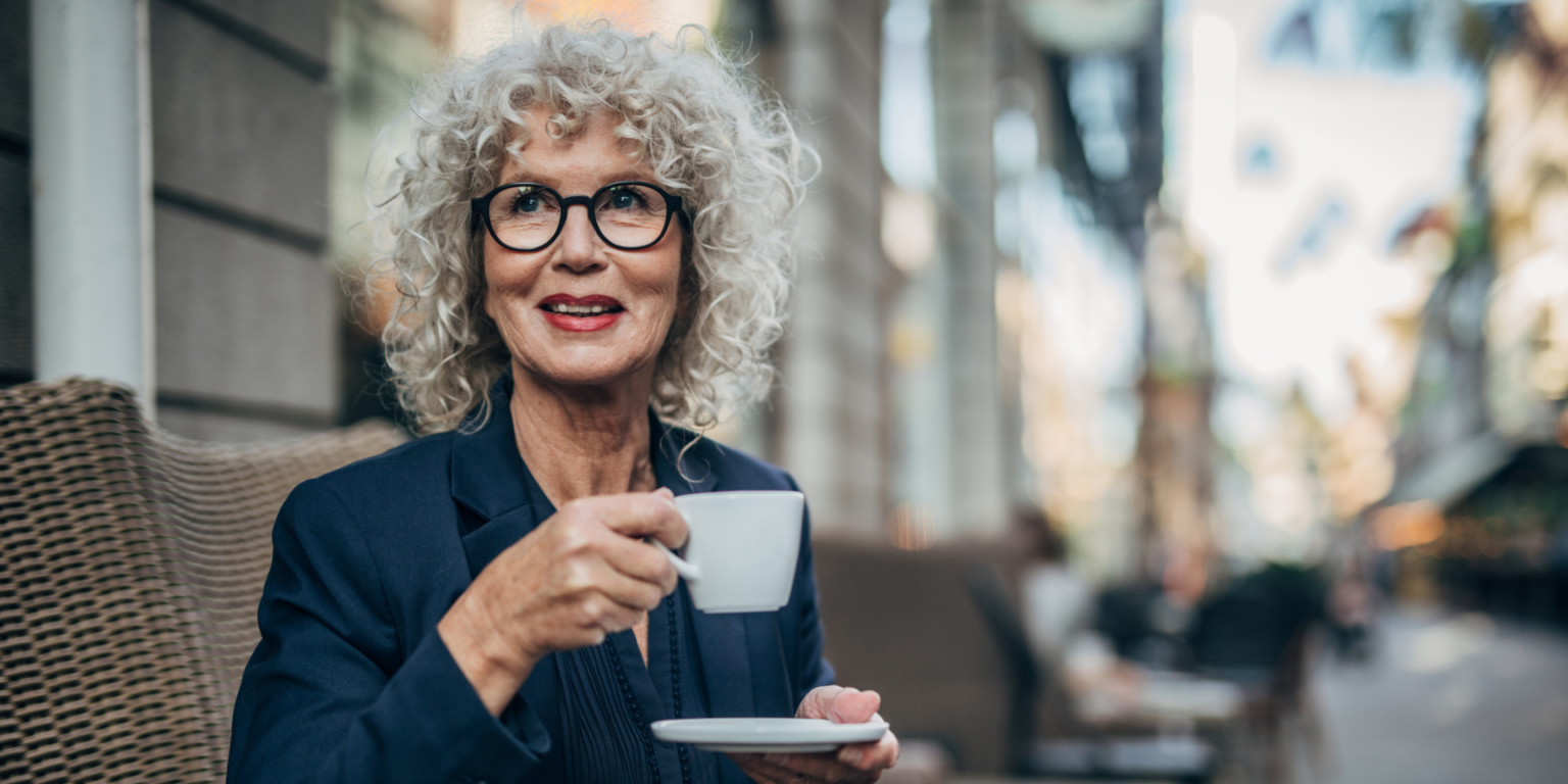 Beautiful senior woman drinking a hot drink in coffee shop