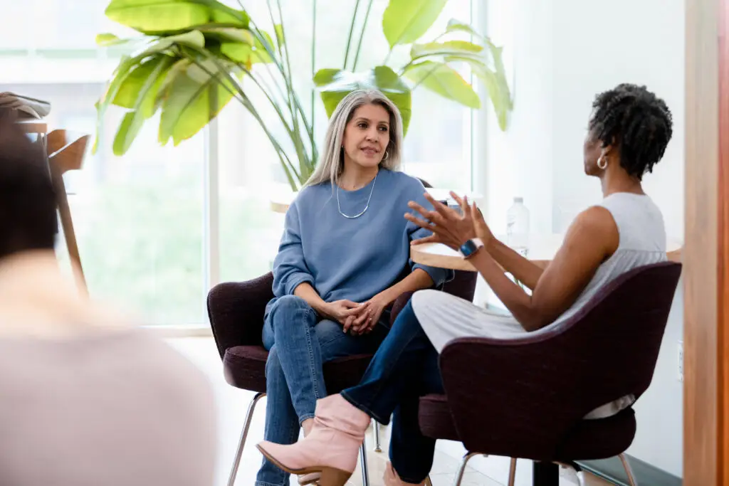 The diverse mature adult female friends meet at a coffee shop to visit together.