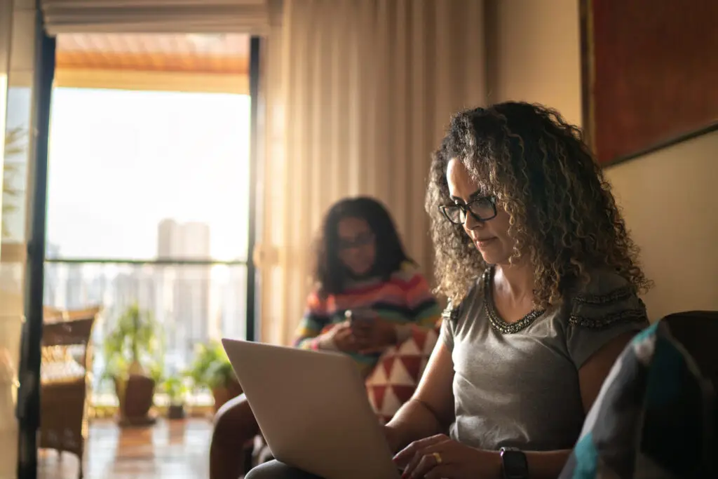 Woman working at home, using laptop sitting on the couch