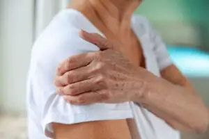 A woman grasping her arm to indicate shoulder pain