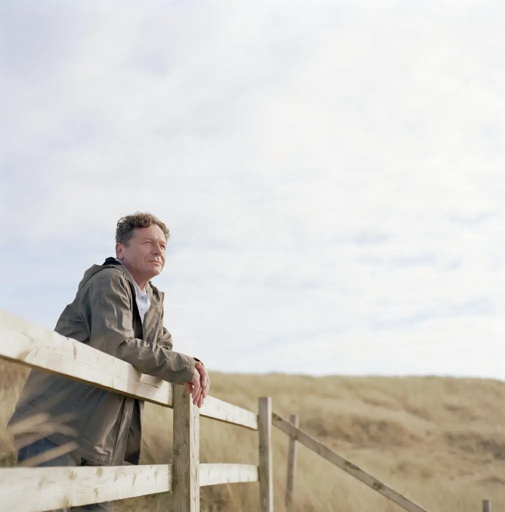 Man leaning on wooden rail outdoors