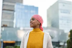 Young woman with pink cancer scarf in front of city high rises