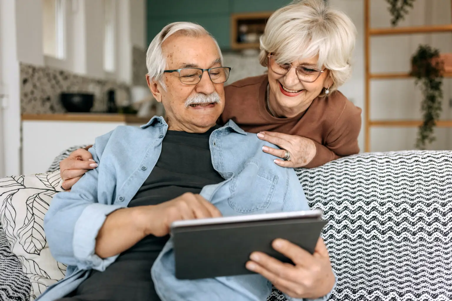 senior couple at home looking at a tablet together
