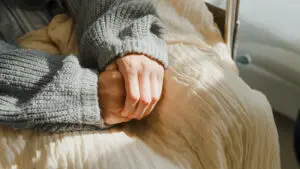 close up of hands of woman in sweater and blanket