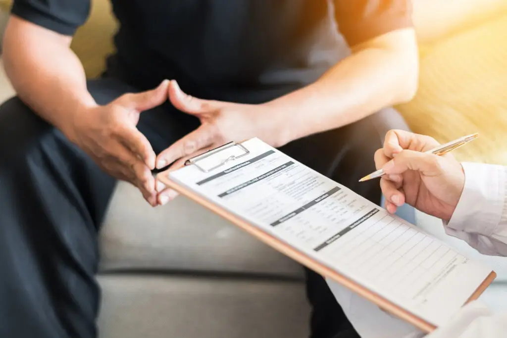 close up of doctor consulting male patient with a clipboard