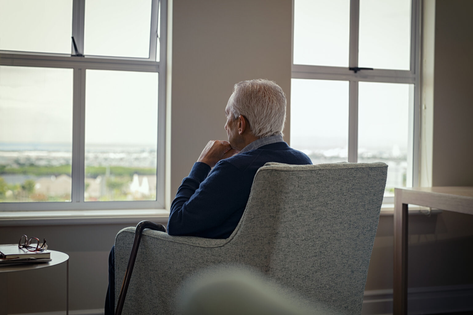 older man looking at the window sitting on armchair