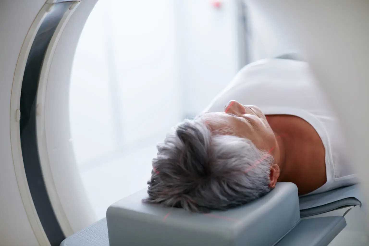 older woman in white shirt undergoing a PET scan