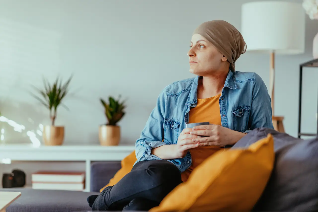 side profile of a woman with breast cancer sitting on the couch at home