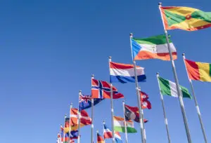 waving in the wind flags of different countries with blue sky on background