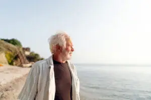 older man on the beach gazing out to the ocean side profile