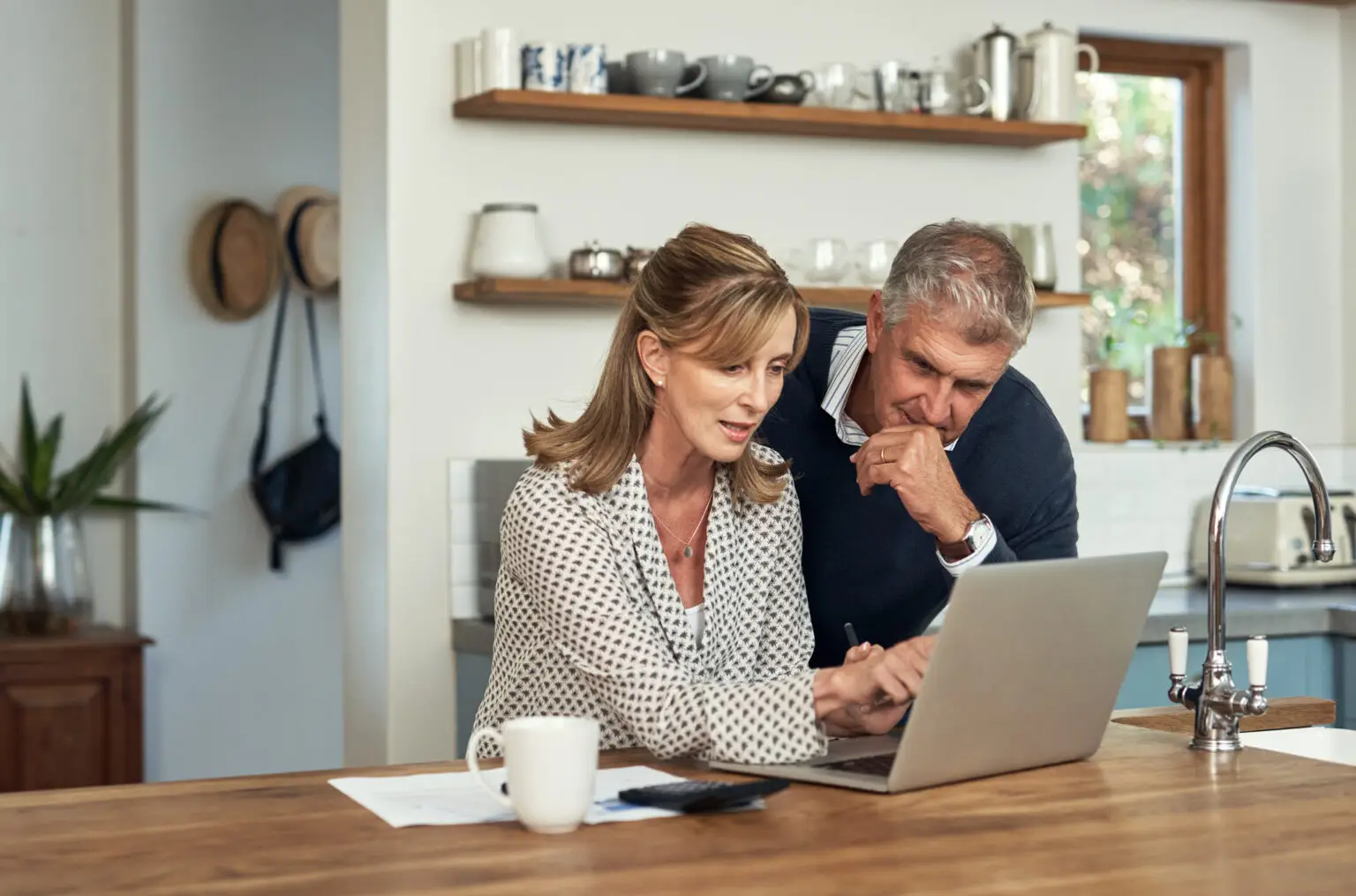 A senior couple planning at home reviewing paperwork on computer