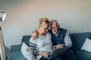 Elderly couple sitting on the sofa holding a laptop computer