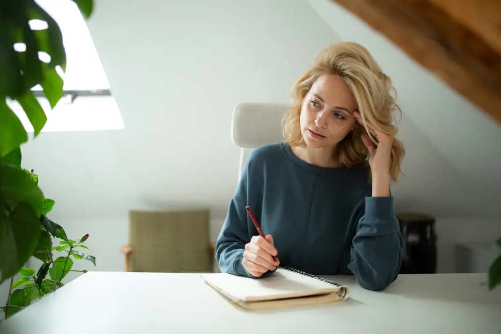 woman at home sitting at desk with a notebook
