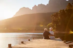 an older couple sitting on the dock by the lake during sunset