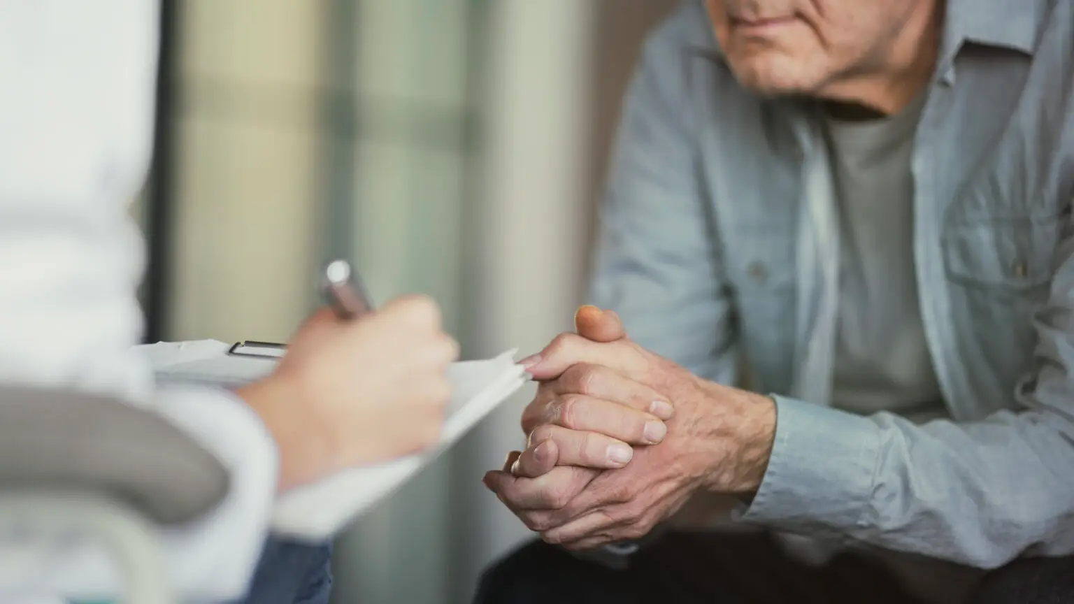 Doctor talks with patient and takes notes close up