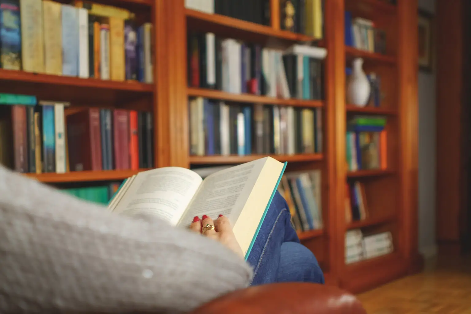 woman reading a book in an armchair in a reading room