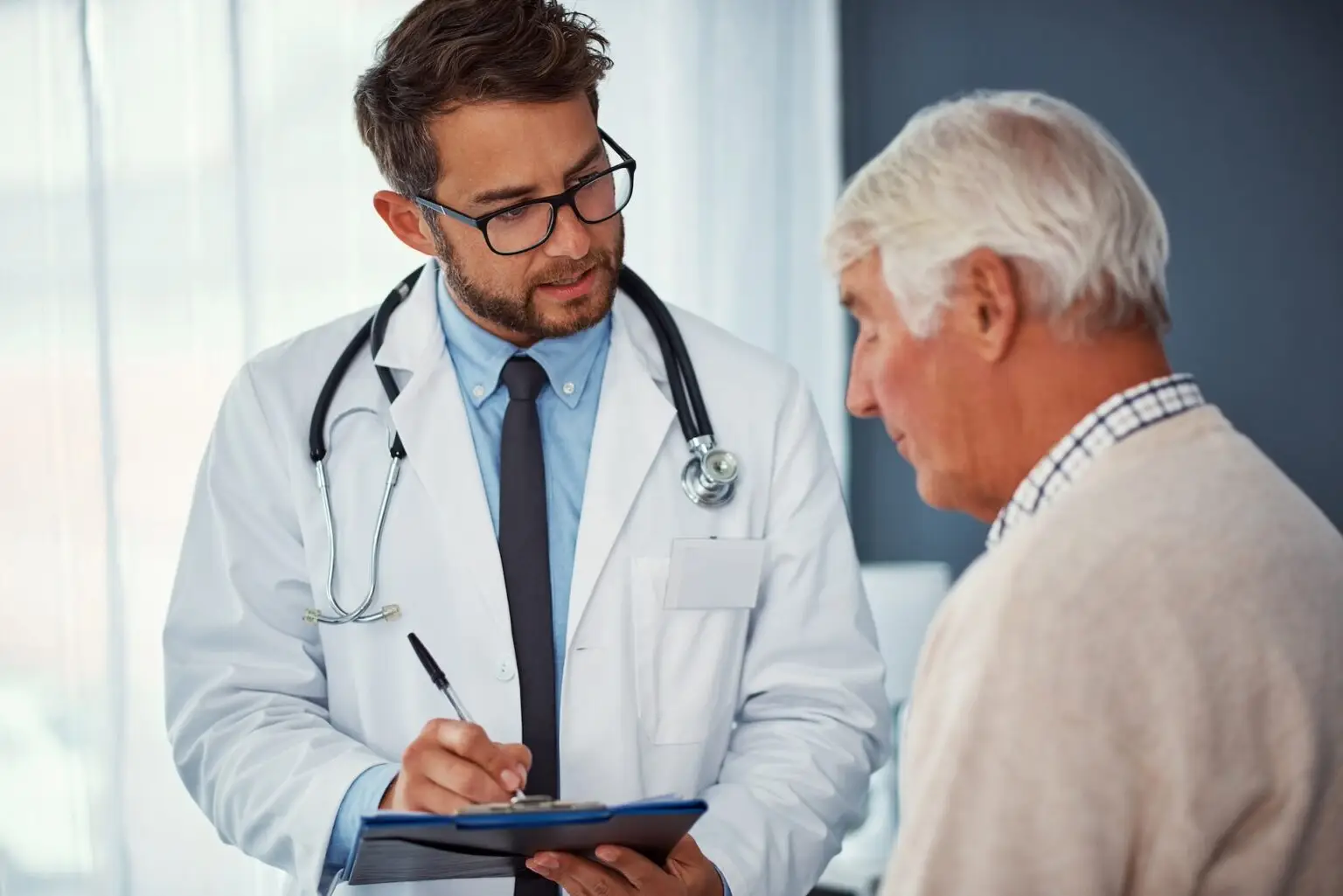 Shot of a doctor writing notes while examining a senior patient in a clinic