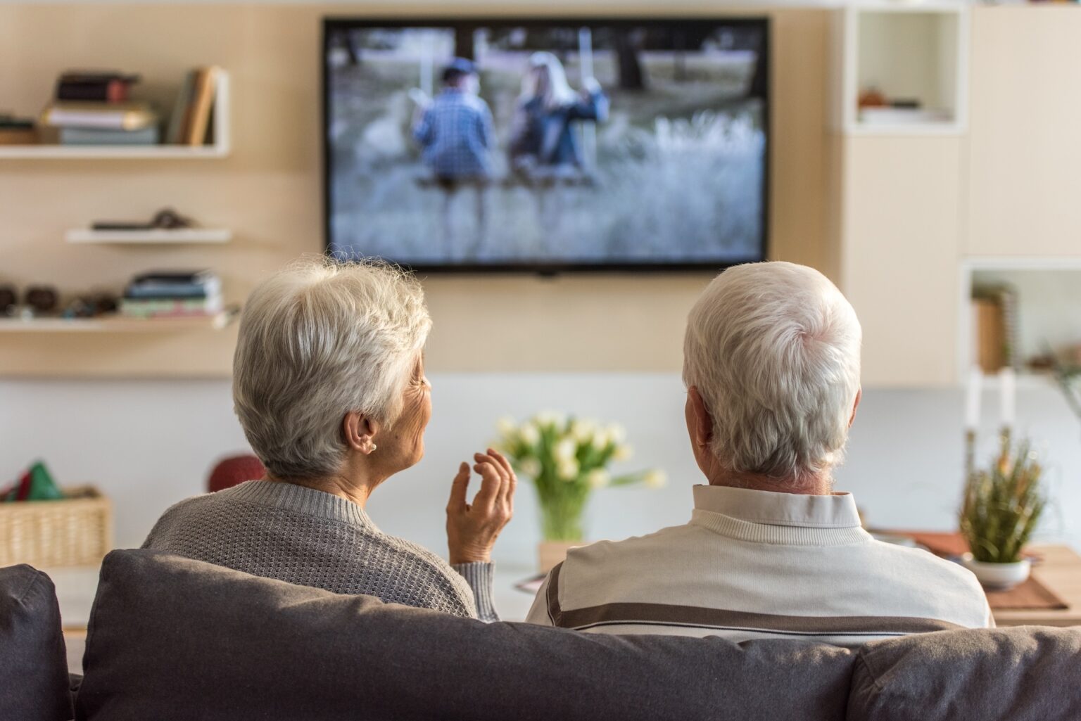 Senior couple sitting on sofa and watching television at home