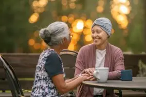 two women talking outside with hot drinks