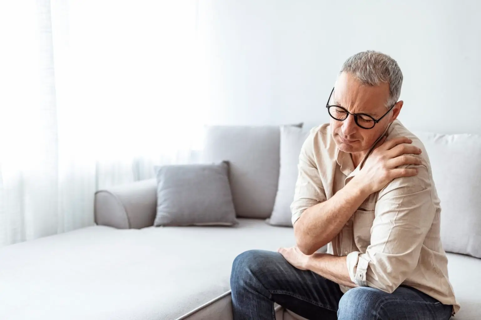 Shot of an mature man holding his shoulder on a couch