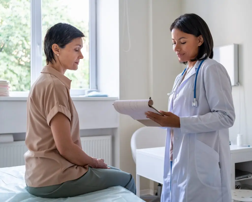 doctor with a clipboard talking to female patient in clinic