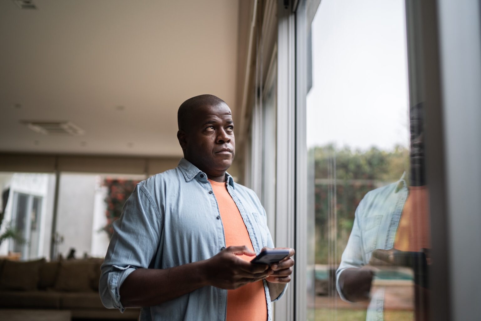 Men contemplating holding a smartphone at home