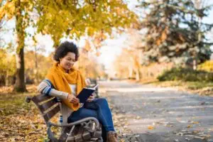 woman reading outside on the bench during fall