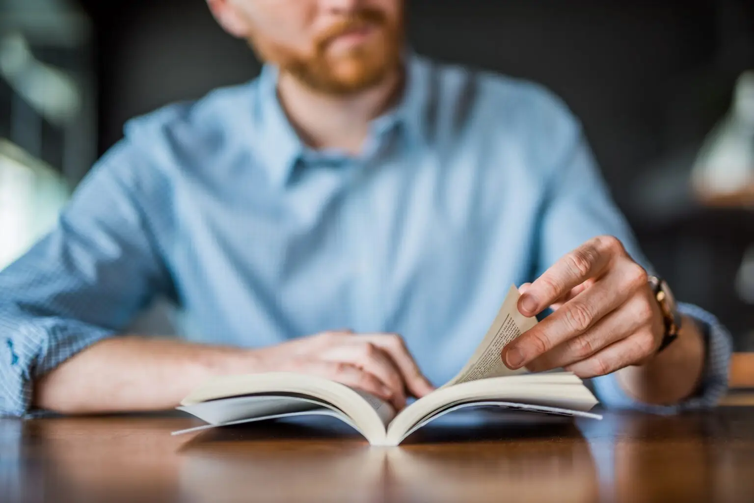 man reading a book at a table close up at a