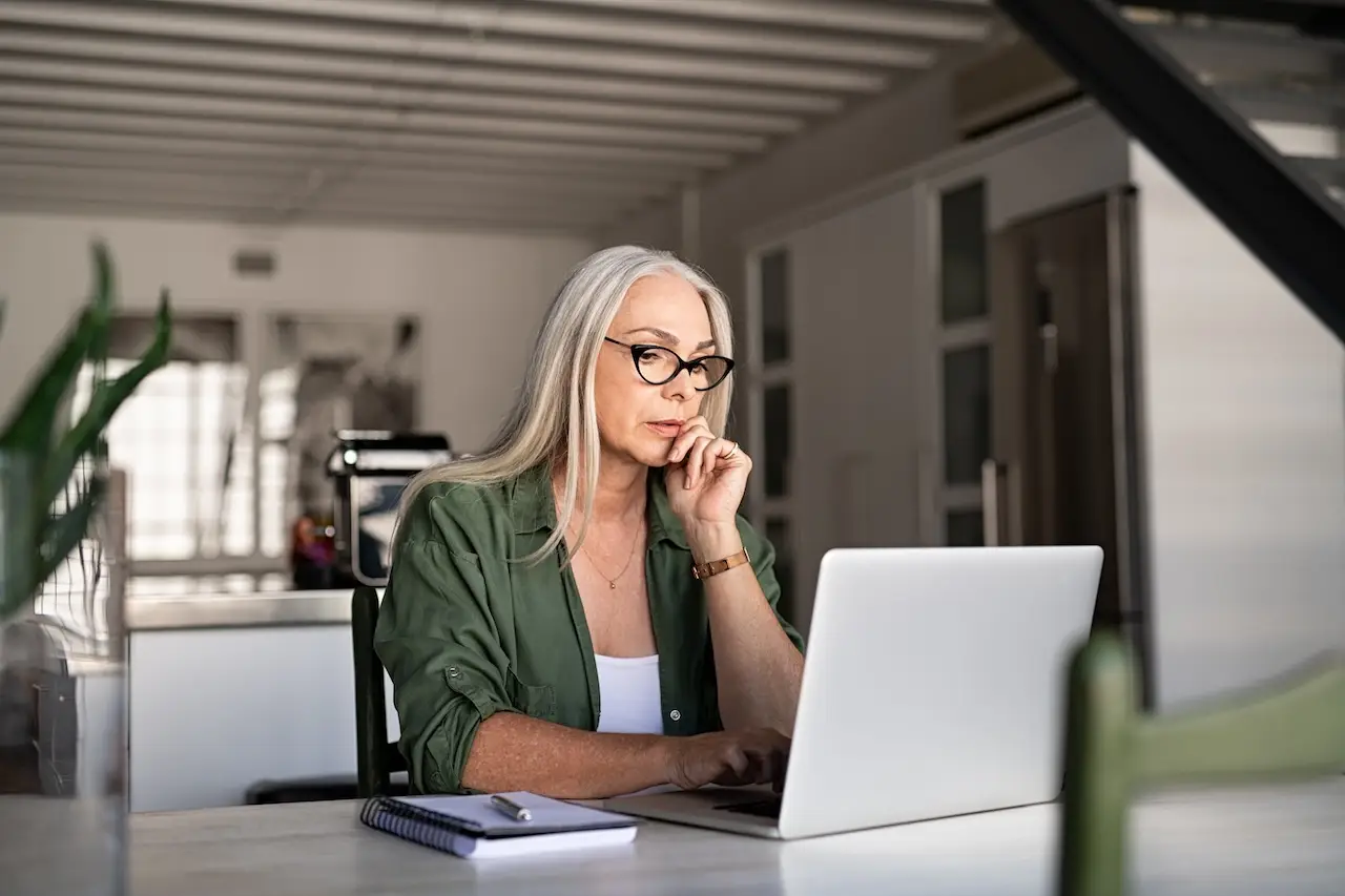 older woman looking at her laptop in a modern home