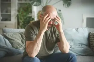 mature man sitting on the couch with head in hands