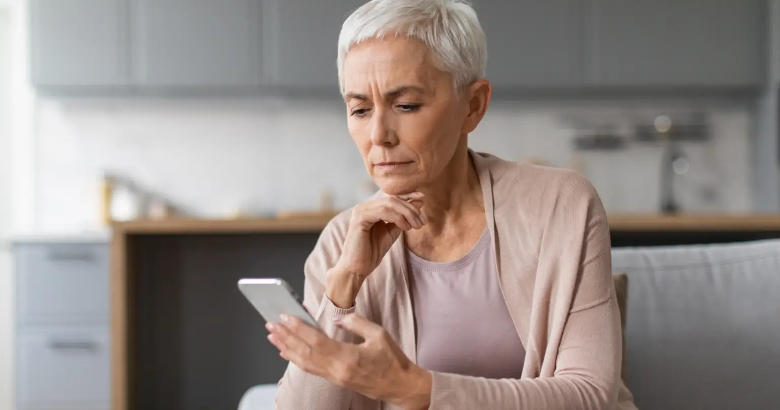 mature woman on smartphone at home on the couch