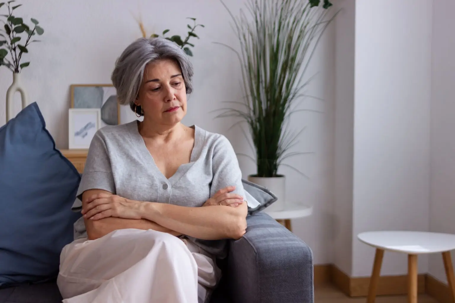 older woman sitting on the couch thinking looking down