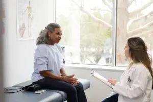 doctor with a clipboard speaking to female patient in clinic