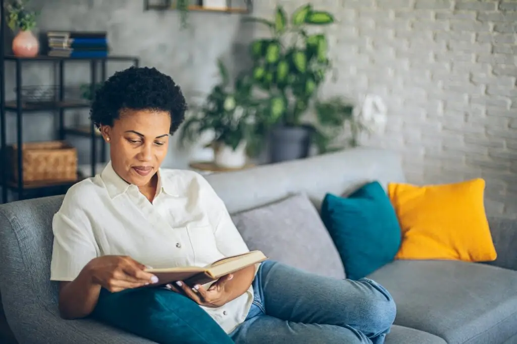 woman reading book at home on the couch