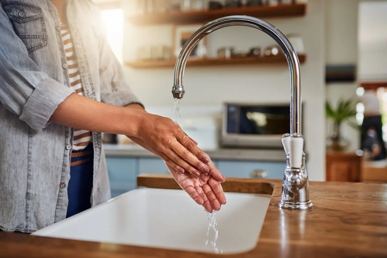 close up of woman washing her hands in kitchen sink