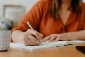 a woman making a to do list in a notebook close up