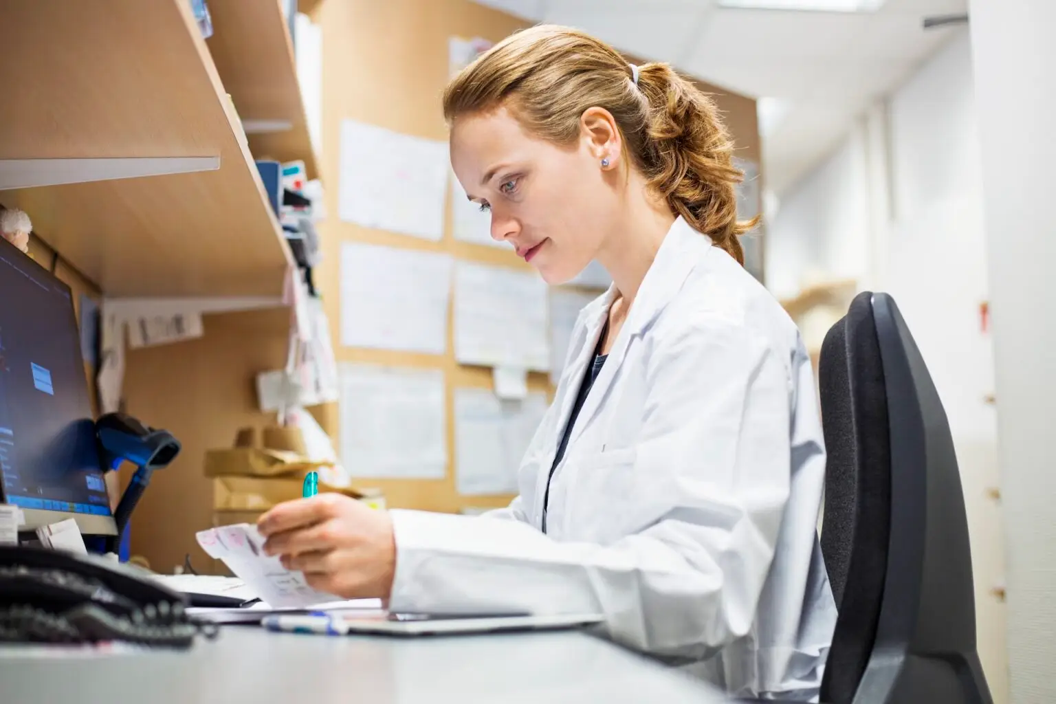 pharmacist looking at prescription while sitting at desk