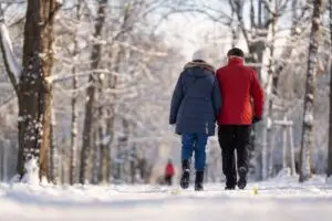 older cpiple walking in park on winter day with snow