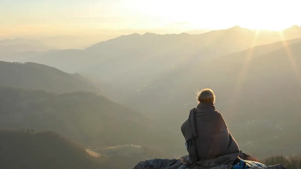 Woman relaxes on mountain ridge at sunrise