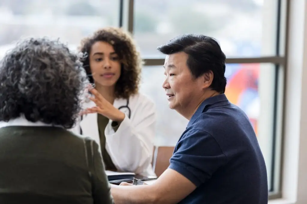older couple sitting with doctor in an office having a conversation