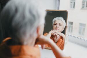 older woman looking at self reflection in mirror