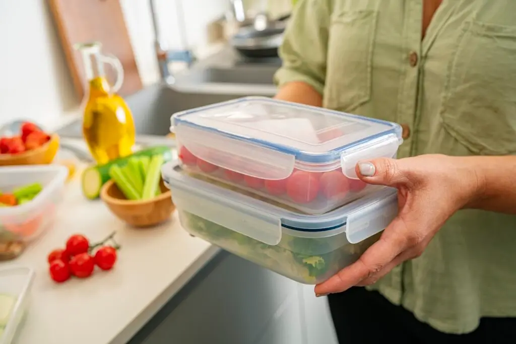 Woman holding plastic food containers filled with vegetables ready for be stored in the refrigerator
