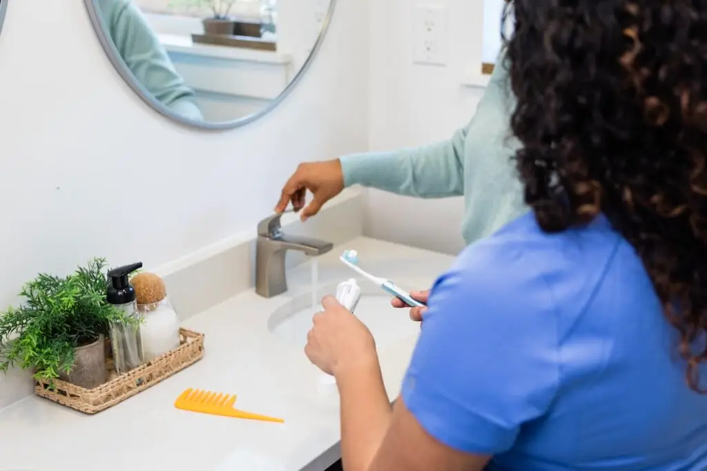 nurse helping patient with oral hygiene dental health in bathroom