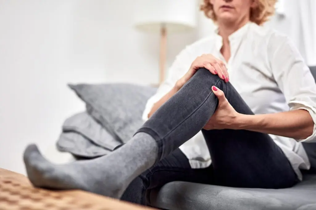 older woman with leg cramps and pain on the couch